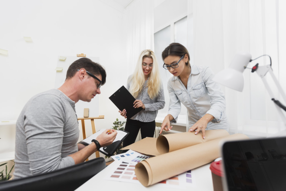 Marketing team reviewing commercial printing campaign materials and color swatches during a print production planning session.