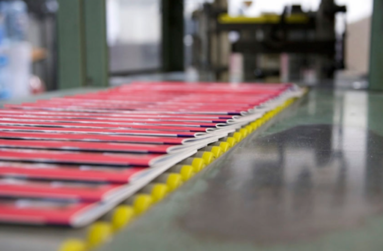 Freshly printed brochures moving along an offset printing production line.